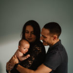 Photographie d'un couple avec leur bébé dans les bras.